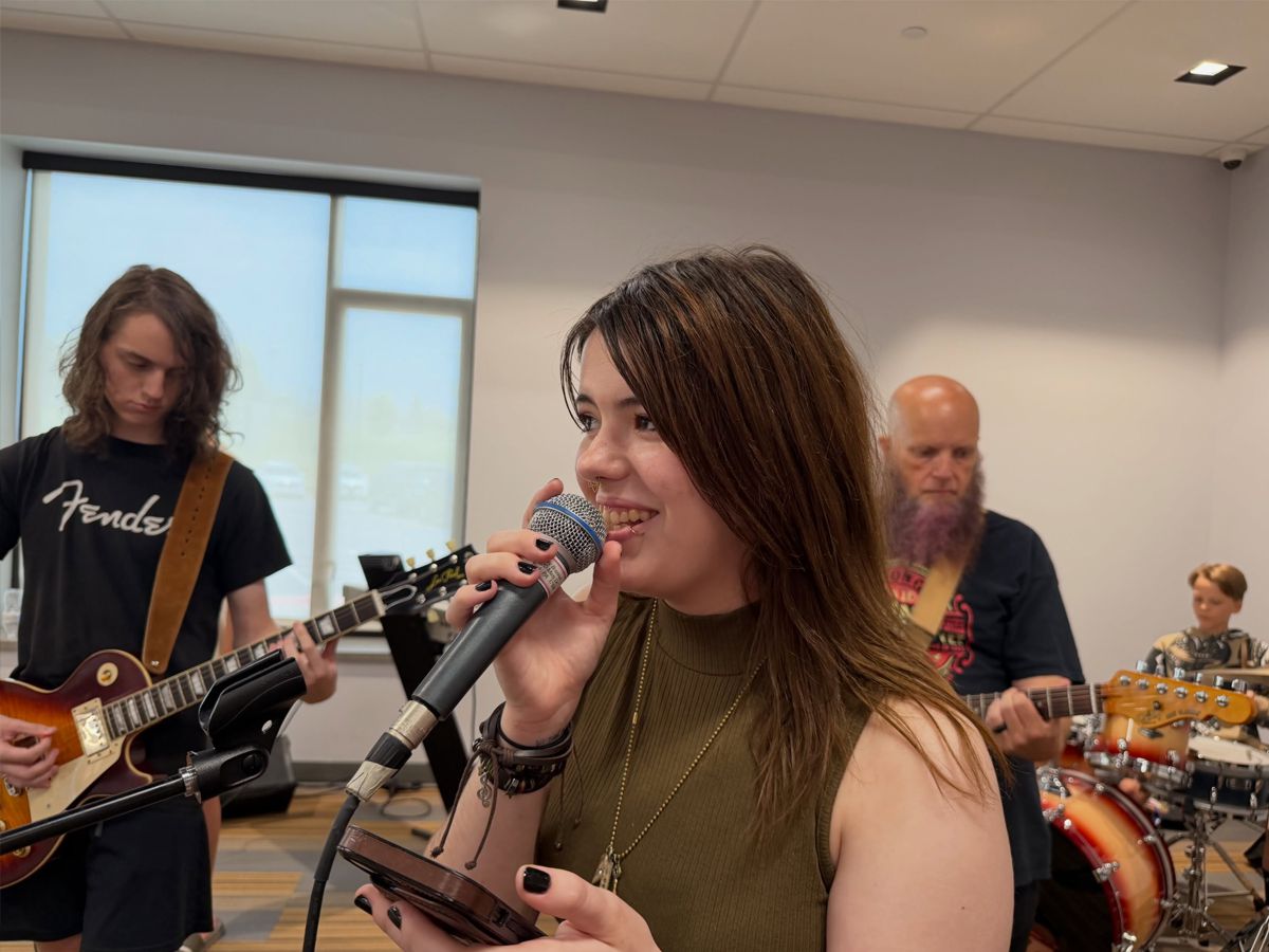A Band Lab vocalist sings lead while bandmates back her on guitar and drums