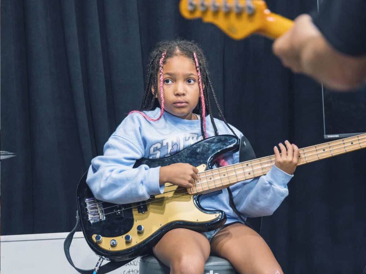 A young student playing electric bass during a Guitar Lab class